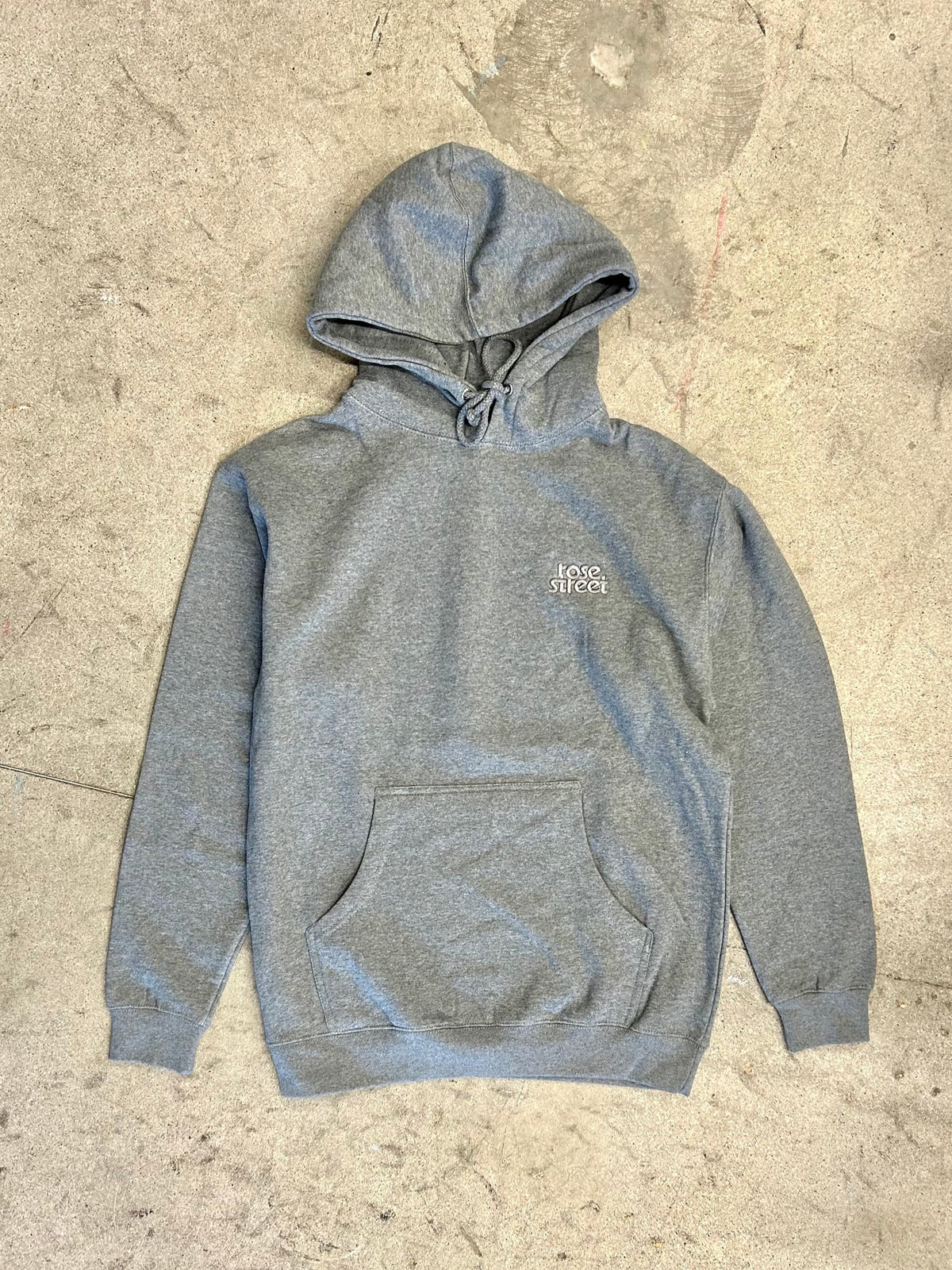 Gray hoodie with a brand logo on a textured beige surface