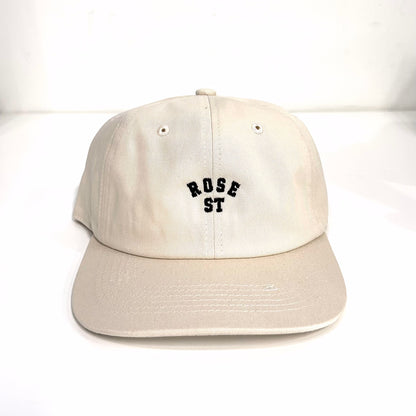 A beige flat-brimmed hat with the 'rose street' logo embroidered in black on the front.