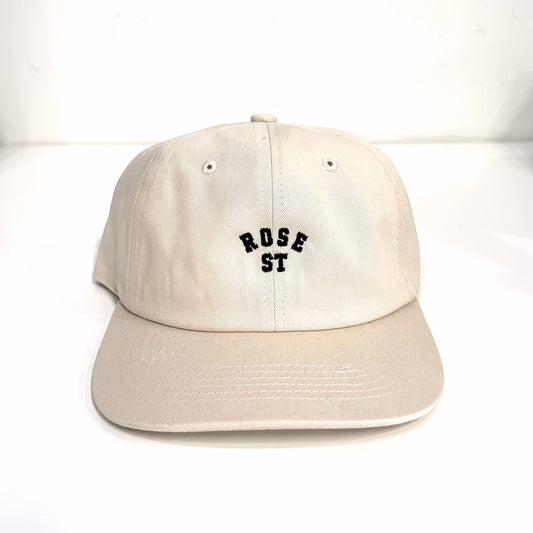 A beige flat-brimmed hat with the 'rose street' logo embroidered in black on the front.